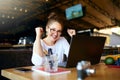 Portrait of happy young business woman celebrating success with arms up in front of laptop. Mixed race female won a lot Royalty Free Stock Photo