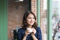 Portrait of happy young business woman with mug in hands drinking coffee in the morning at restaurant Royalty Free Stock Photo