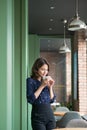 Portrait of happy young business woman with mug in hands drinking coffee in the morning at restaurant Royalty Free Stock Photo