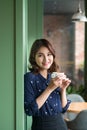 Portrait of happy young business woman with mug in hands drinking coffee in the morning at restaurant Royalty Free Stock Photo