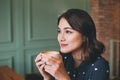 Portrait of happy young business woman with mug in hands drinking coffee in the morning at restaurant Royalty Free Stock Photo