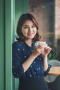 Portrait of happy young business woman with mug in hands drinking coffee in the morning at restaurant Royalty Free Stock Photo