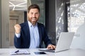Portrait of a happy young businessman showing a hand gesture of success and victory to the camera. He sits in the office Royalty Free Stock Photo