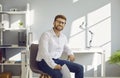 Portrait of a happy young businessman sitting on a chair by his desk in the office Royalty Free Stock Photo