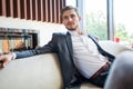 Portrait of happy young businessman sitting on sofa in hotel lobby. Royalty Free Stock Photo