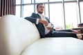 Portrait of happy young businessman sitting on sofa in hotel lobby. Royalty Free Stock Photo