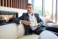 Portrait of happy young businessman sitting on sofa in hotel lobby. Royalty Free Stock Photo