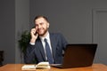 Portrait of happy young businessman using laptop computer and talking on smartphone Royalty Free Stock Photo