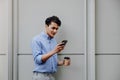 Portrait of a Happy Young Businessman Using Mobile Phone. Lifestyle of Modern People. Standing by the Wall Royalty Free Stock Photo