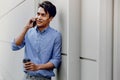 Portrait of a Happy Young Businessman Using Mobile Phone. Lifestyle of Modern People. Standing by the Wall Royalty Free Stock Photo