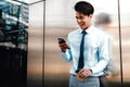 Portrait of a Happy Young Businessman Using Mobile Phone in the Urban City. Lifestyle of Modern People. Standing by the Wall with Royalty Free Stock Photo