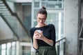 A portrait of young businesswoman with smartphone standing in corridor outside office. Royalty Free Stock Photo