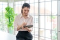 Portrait of happy young businesswoman looking at business document in tablet, standing near the window in office Royalty Free Stock Photo