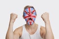 Portrait of happy young Caucasian man with British flag painted on face celebrating success against white background Royalty Free Stock Photo