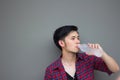 Portrait of a happy young Caucasian man drinking water from plastic bottle on gray background. Royalty Free Stock Photo