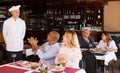 Happy chef of pizza restaurant listening to praises of guests