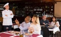 Happy chef of pizza restaurant listening to praises of guests