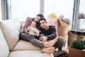 A portrait of young couple with a baby and cardboard boxes moving in a new home. Royalty Free Stock Photo