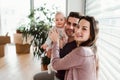 A portrait of young couple with a baby and cardboard boxes moving in a new home. Royalty Free Stock Photo