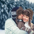 Portrait happy young couple in love at winter day, man gentle kissing woman wearing hat and knitted sweater Royalty Free Stock Photo