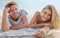 Portrait of happy young couple lying on blanket and enjoying beach vacation. Smiling young blonde man and woman relaxing Royalty Free Stock Photo