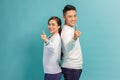 Portrait of happy young couple man and woman smiling and pointing fingers at camera isolated over blue background Royalty Free Stock Photo