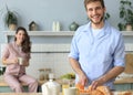 Portrait of happy young couple in pajamas cooking together in the kitchen, drinking orange juice in the morning at home Royalty Free Stock Photo