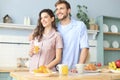 Portrait of happy young couple in pajamas cooking together in the kitchen, drinking orange juice in the morning at home Royalty Free Stock Photo
