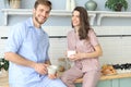 Portrait of happy young couple in pajamas cooking together in the kitchen, drinking orange juice in the morning at home Royalty Free Stock Photo