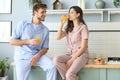 Portrait of happy young couple in pajamas cooking together in the kitchen, drinking orange juice in the morning at home Royalty Free Stock Photo