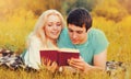 Portrait of happy young couple reading book together lying on the grass in the park Royalty Free Stock Photo