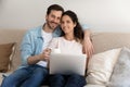 Portrait happy young couple sitting on couch with laptop Royalty Free Stock Photo