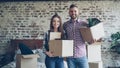 Portrait of happy young couple standing in new house, holding carton boxes, smiling and looking at camera. Family Royalty Free Stock Photo