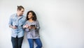 Portrait of happy young couple using smartphone standing isolated over white wall background. Royalty Free Stock Photo