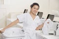 Portrait of a happy young employee putting clothes in washing machine