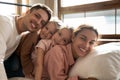 Portrait of happy young family with kids relaxing in bedroom Royalty Free Stock Photo