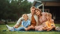 Portrait of a Happy Young Family with Kids Sitting on a Lawn in Their Front Yard on a Warm Summer Royalty Free Stock Photo