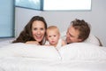 Portrait of a happy young family lying in bed with cute baby Royalty Free Stock Photo