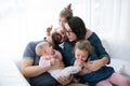 A portrait of young family with small children sitting indoors on a sofa, having fun.