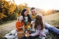 A young family with two small children having picnic in autumn nature at sunset. Royalty Free Stock Photo