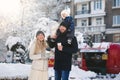 Portrait of a happy young family walking together in a winter city park, sunlight. The son is sitting on Dad& x27;s neck Royalty Free Stock Photo