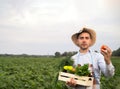 Portrait of a happy young farmer holding fresh vegetables in a basket. On a background of nature The concept of biological, bio Royalty Free Stock Photo