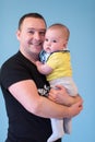 Portrait of happy young father holding baby isolated on blue Royalty Free Stock Photo