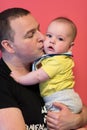Portrait of happy young father holding baby isolated on red Royalty Free Stock Photo