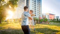 Portrait of happy young father hugging and spinning his smiling little toddler son in park