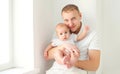 Portrait happy young father with little baby at home near window in white room Royalty Free Stock Photo