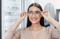 Portrait of happy young female customer choosing spectacles Royalty Free Stock Photo