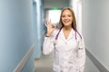 Portrait of happy young female doctor standing in hospital corridor with okay sign. Caucasian woman working in nursing home Royalty Free Stock Photo