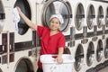 Portrait of a happy young female employee putting clothes in washer