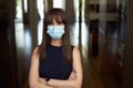 Portrait of happy young female office worker in office building hallway, wearing face mask Royalty Free Stock Photo